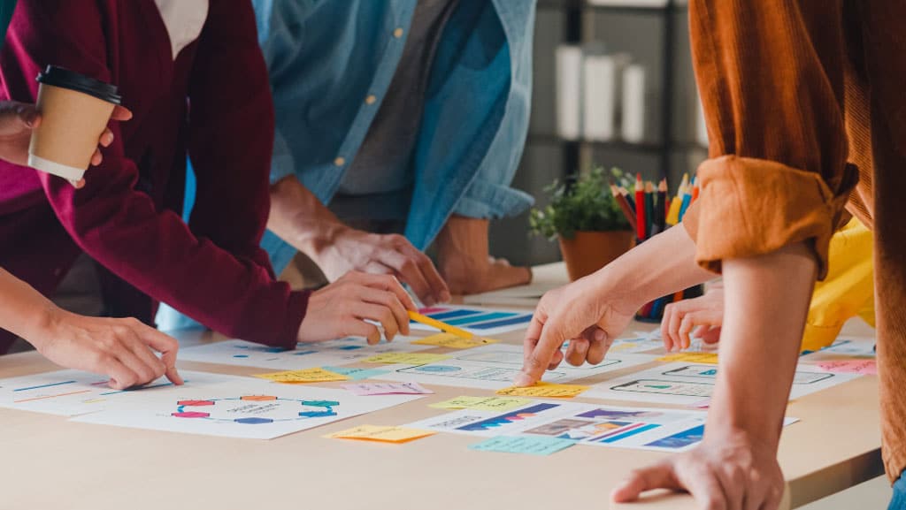 4 personnes collaborent autour de documents sur un bureau imageant la sous-traitance