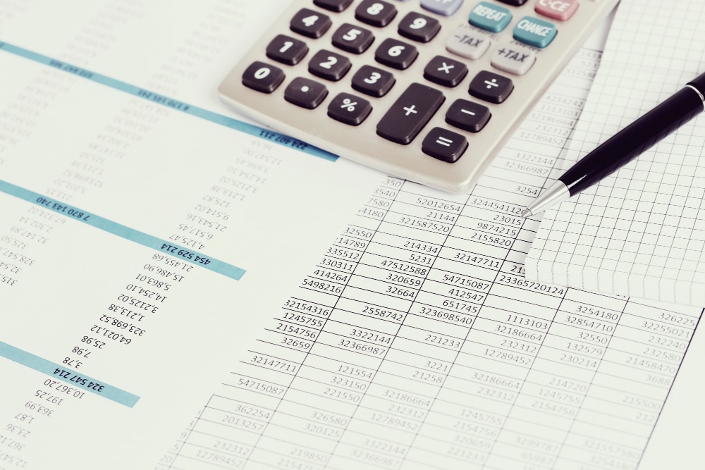 Tableaux comptables posés sur un bureau avec un stylo et une calculatrice